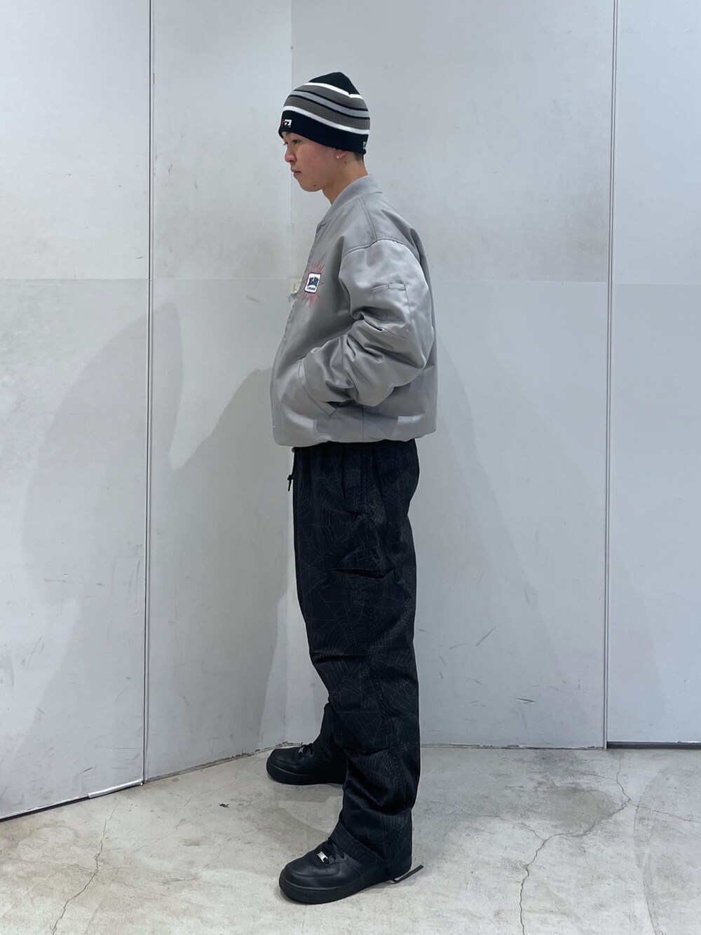 グレー系のブルゾン、ブラック系のその他パンツ、ブラック系のニットキャップ/ビーニーを着用したメンズの冬コーディネートの4枚目の写真