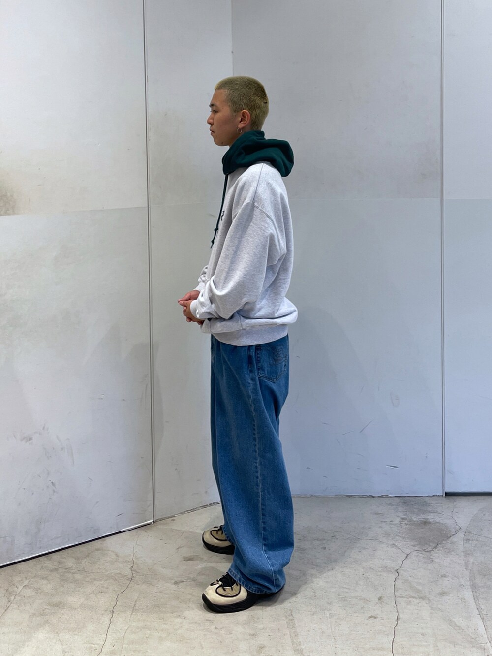 グレー系のパーカー、ブルー系のデニムパンツを着用したメンズの秋コーディネートの4枚目の写真