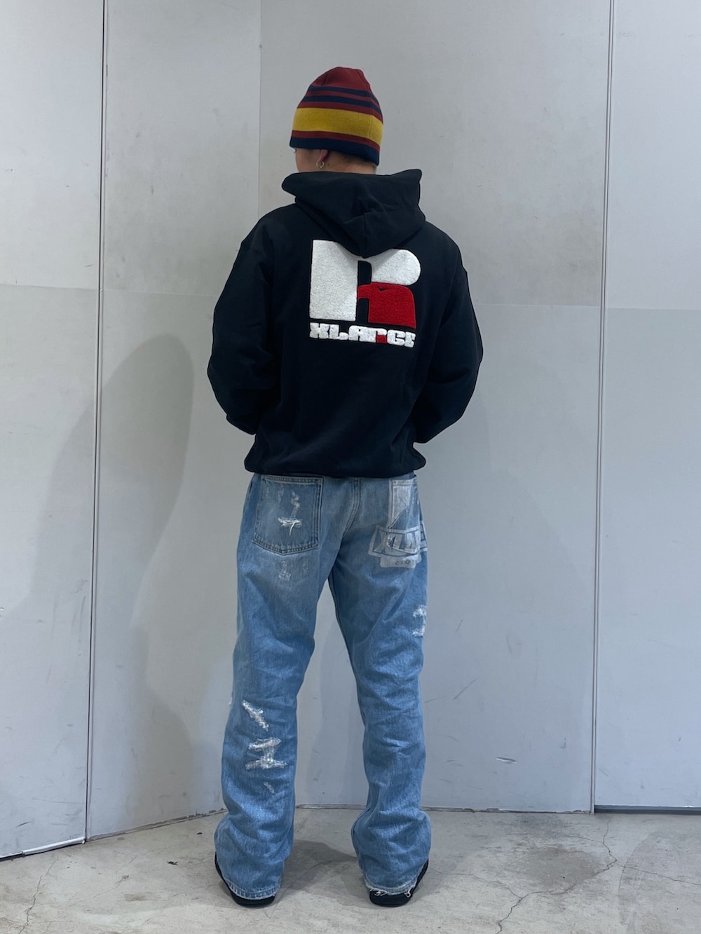 ブルー系のデニムパンツ、ブラック系のパーカー、レッド系のニットキャップ/ビーニーを着用したメンズの秋コーディネートの3枚目の写真