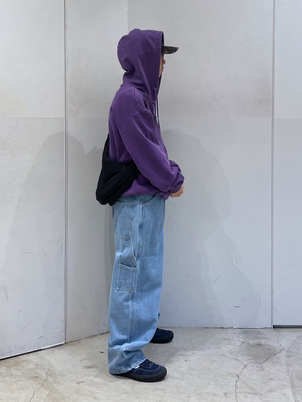 パープル系のパーカー、ブルー系のデニムパンツ、ブラック系のショルダーバッグを着用したメンズの秋コーディネートの2枚目の写真