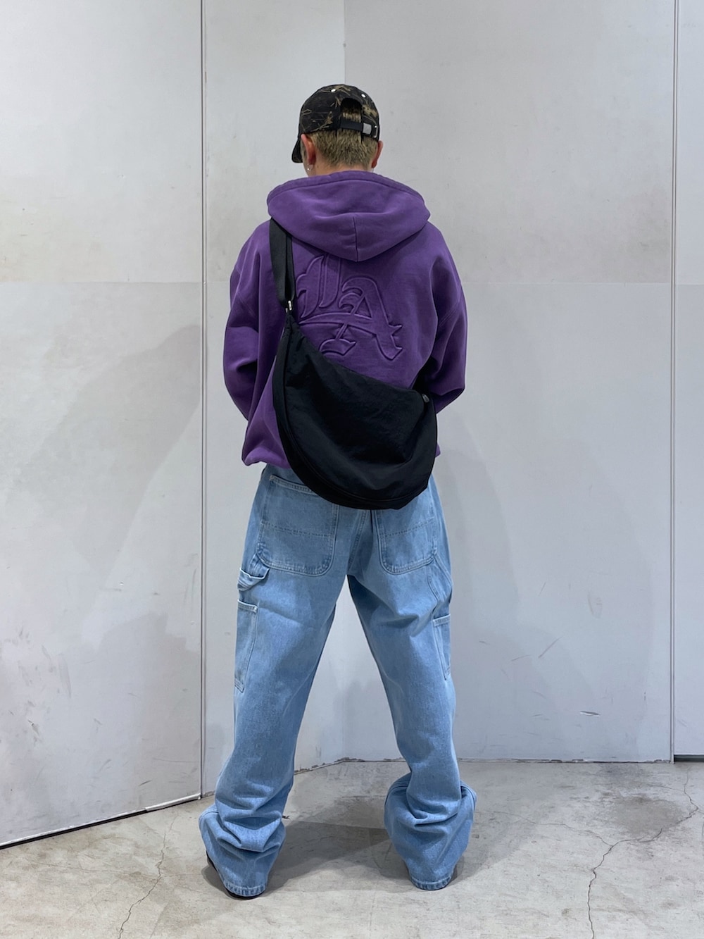 パープル系のパーカー、ブルー系のデニムパンツ、ブラック系のショルダーバッグを着用したメンズの秋コーディネートの4枚目の写真