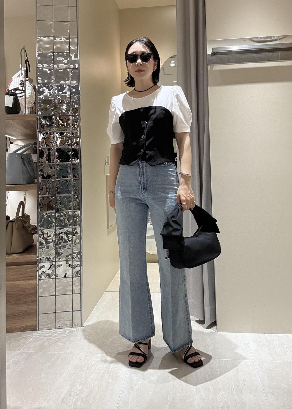 ブルー系のデニムパンツ、ブラック系のハンドバッグ、ブラック系のTシャツ/カットソーを着用したレディースの春コーディネートの2枚目の写真