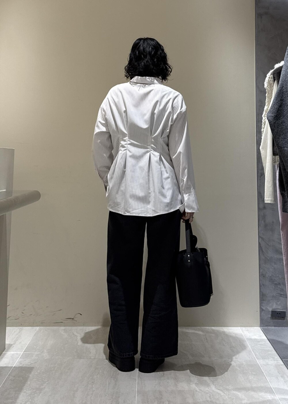 ブラック系のブーツ、ブラック系のショルダーバッグ、グレー系のデニムパンツを着用したレディースの秋コーディネートの4枚目の写真