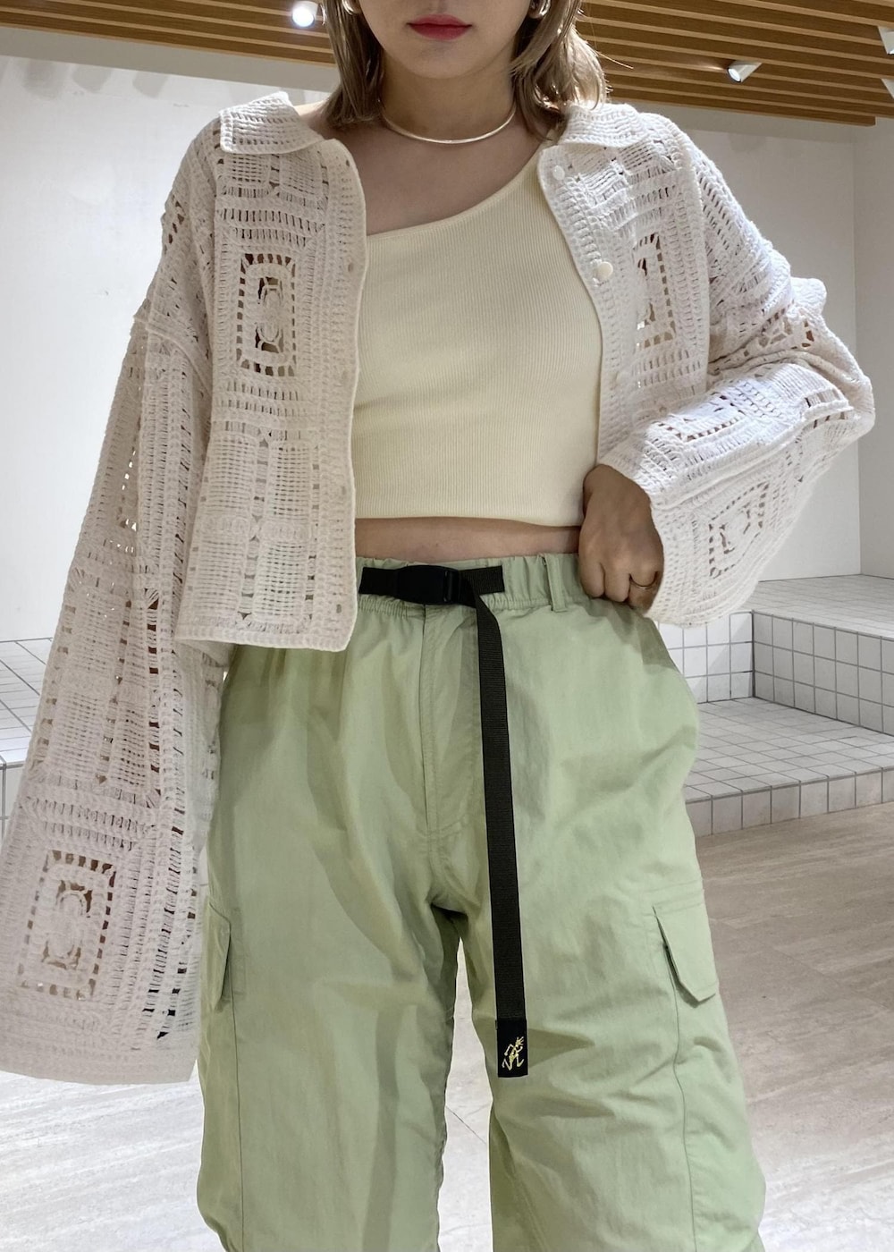 ホワイト系のタンクトップ、ホワイト系のカーディガン/ボレロ、グリーン系のカーゴパンツを着用したレディースの春コーディネートの3枚目の写真