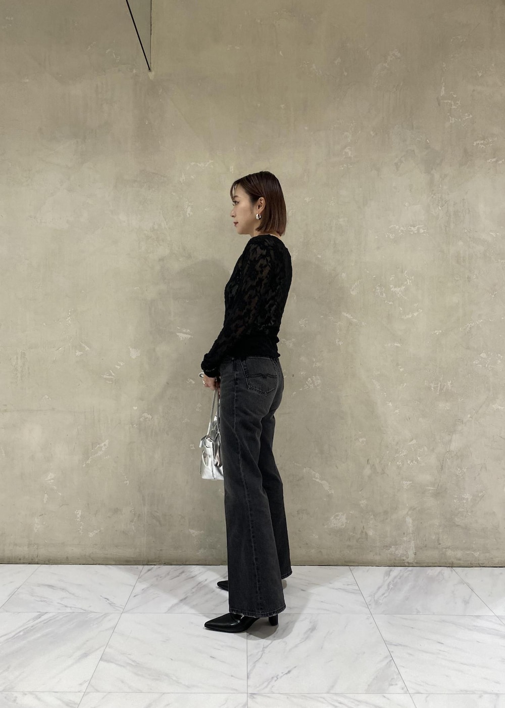 シルバー系のキャミソール、シルバー系のショルダーバッグ、ブラック系のデニムパンツを着用したレディースの秋コーディネートの4枚目の写真