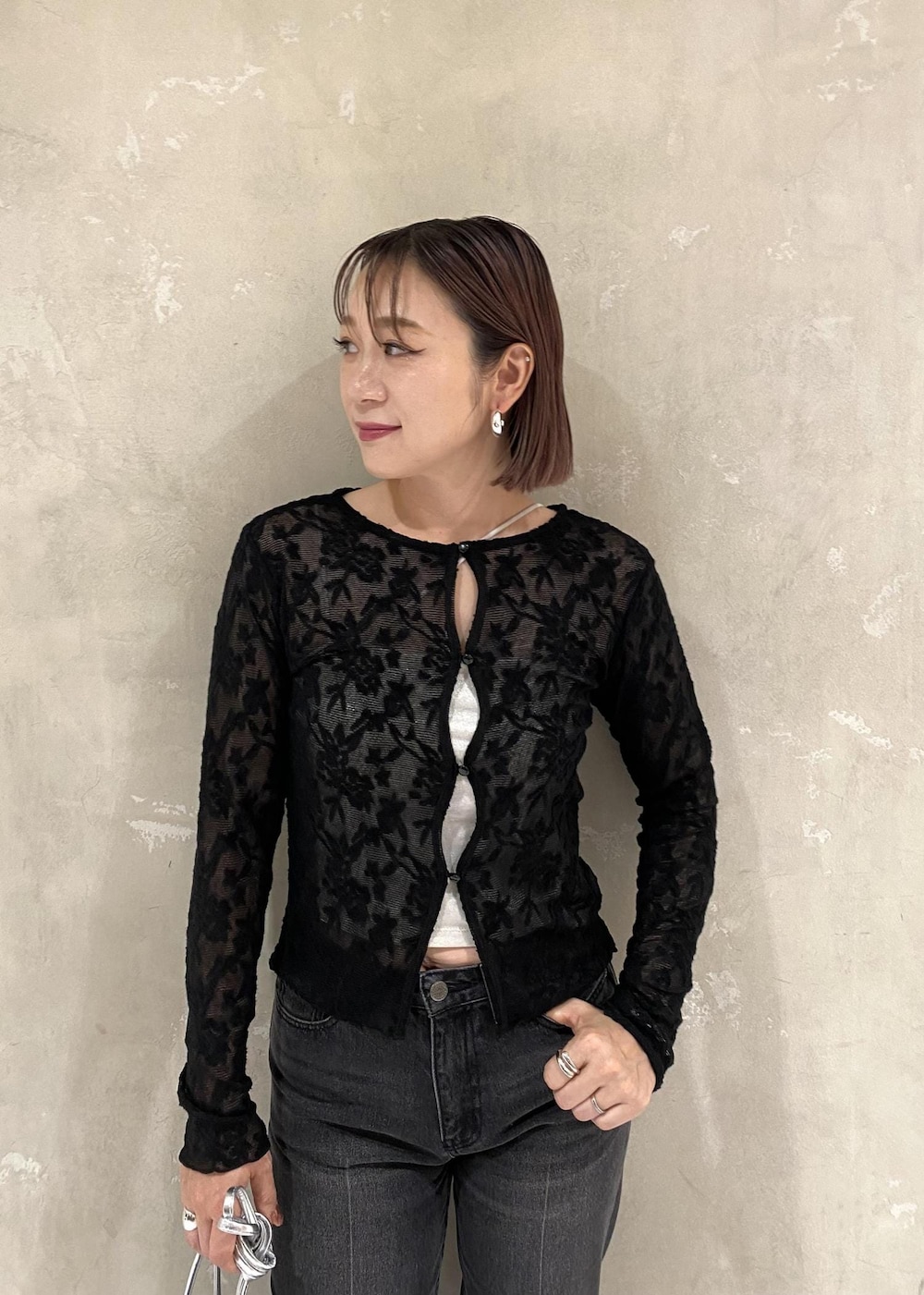 シルバー系のキャミソール、シルバー系のショルダーバッグ、ブラック系のデニムパンツを着用したレディースの秋コーディネートの6枚目の写真