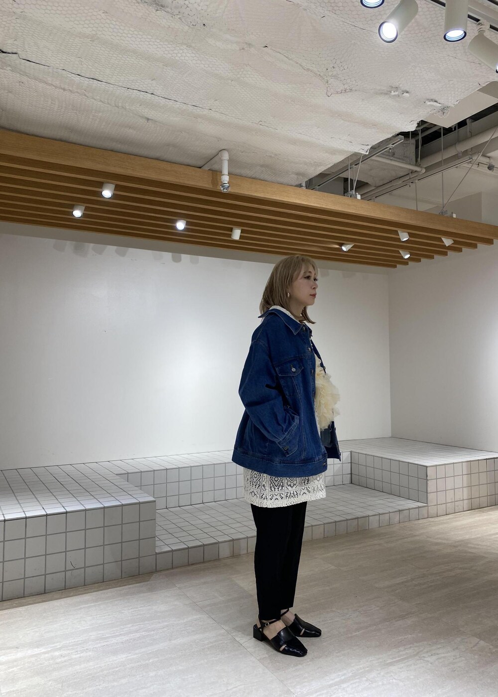 ブルー系のデニムジャケット、ブラック系のサンダル、ホワイト系のワンピースを着用したレディースの春コーディネートの4枚目の写真