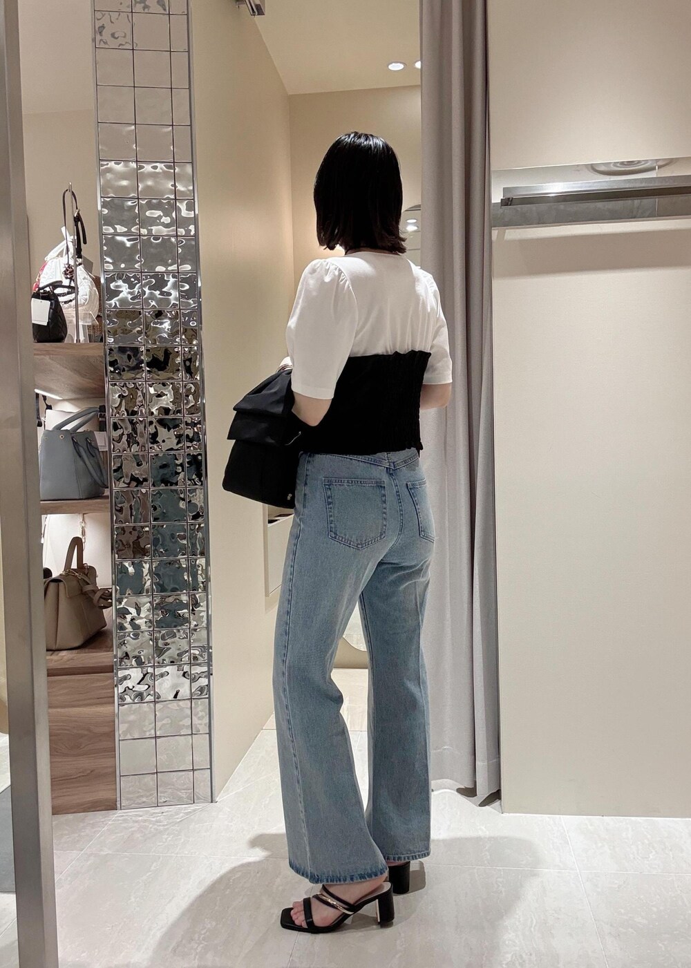 ブルー系のデニムパンツ、ブラック系のハンドバッグ、ブラック系のTシャツ/カットソーを着用したレディースの春コーディネートの3枚目の写真