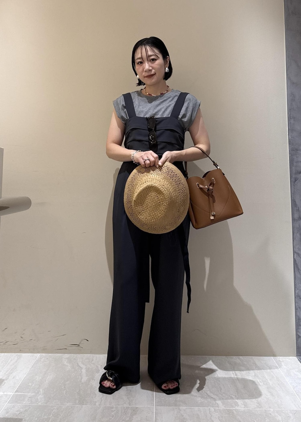 ブラウン系のショルダーバッグ、ブラック系のサンダル、グレー系のTシャツ/カットソーを着用したレディースの夏コーディネートの4枚目の写真