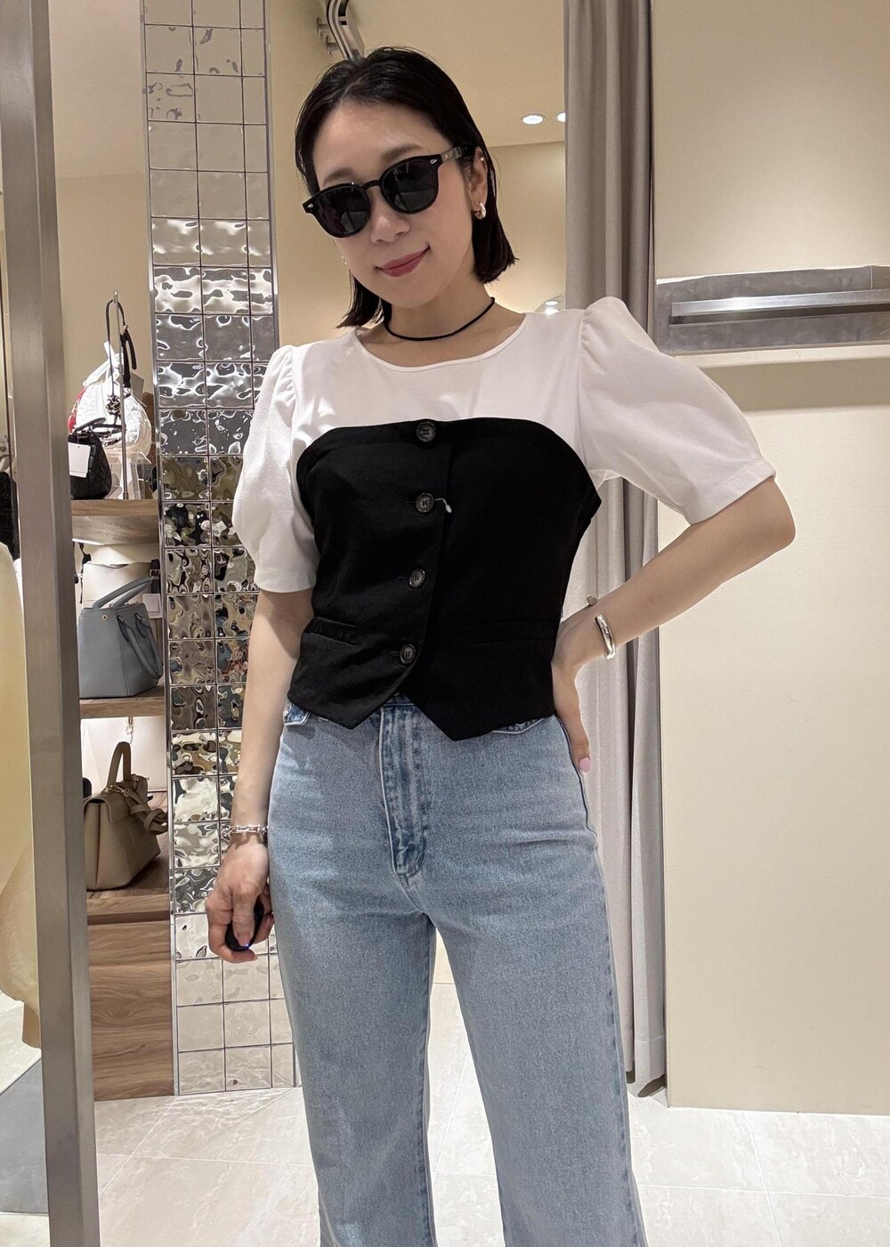 ブルー系のデニムパンツ、ブラック系のハンドバッグ、ブラック系のTシャツ/カットソーを着用したレディースの春コーディネートの5枚目の写真