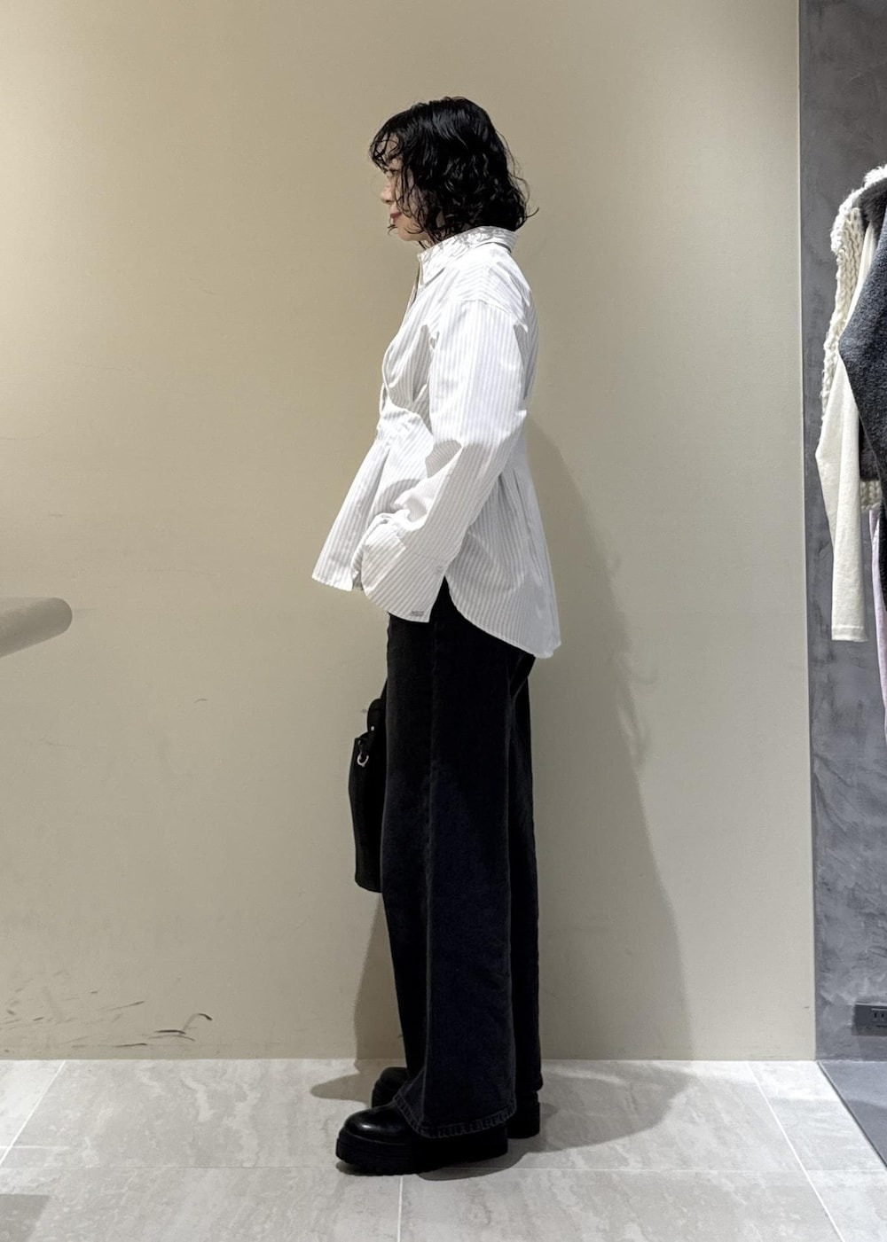 ブラック系のブーツ、ブラック系のショルダーバッグ、グレー系のデニムパンツを着用したレディースの秋コーディネートの5枚目の写真