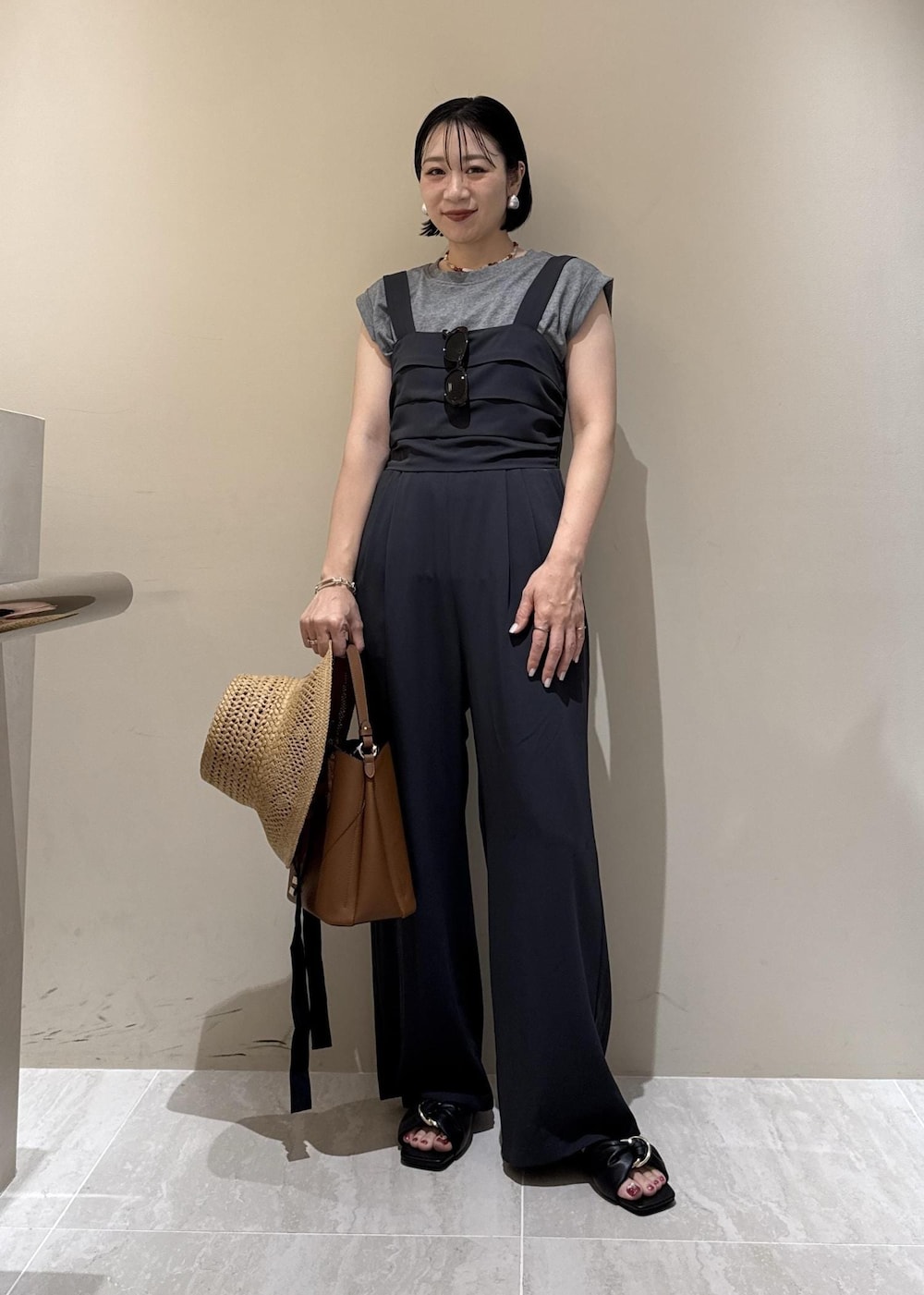 ブラウン系のショルダーバッグ、ブラック系のサンダル、グレー系のTシャツ/カットソーを着用したレディースの夏コーディネートの2枚目の写真