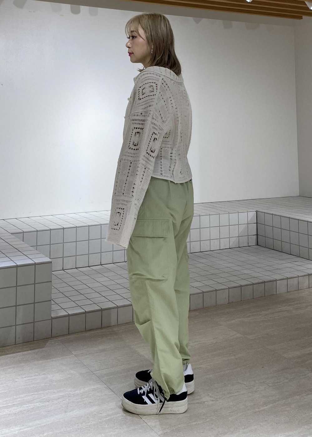 ホワイト系のタンクトップ、ホワイト系のカーディガン/ボレロ、グリーン系のカーゴパンツを着用したレディースの春コーディネートの2枚目の写真