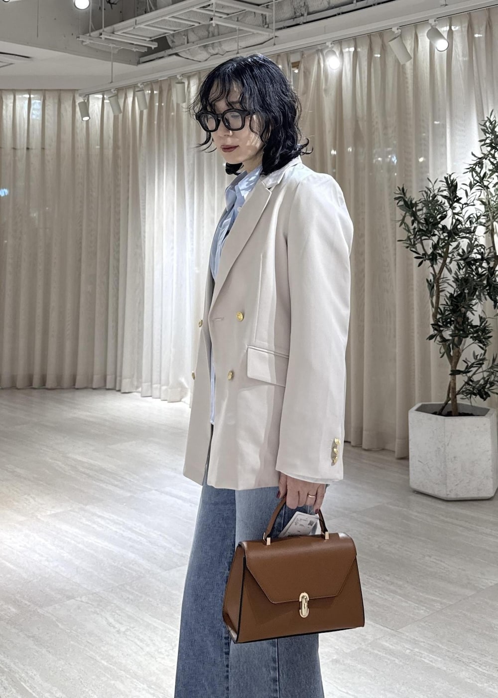 ブラック系のブーツ、イエロー系のハンドバッグ、ブルー系のシャツ/ブラウスを着用したレディースの冬コーディネートの7枚目の写真