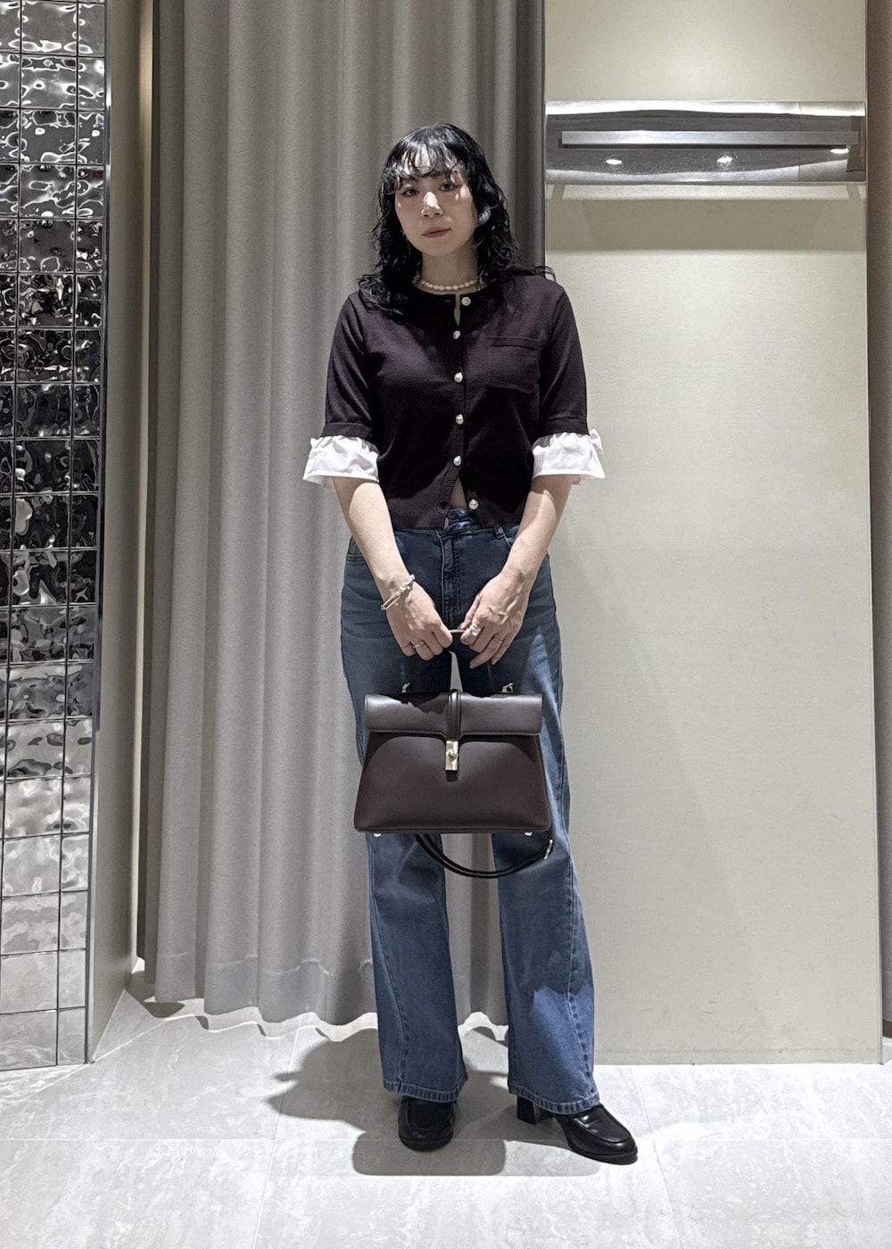 ブラック系のローファー、ブラウン系のカーディガン/ボレロ、ブルー系のデニムパンツを着用したレディースの秋コーディネートの2枚目の写真