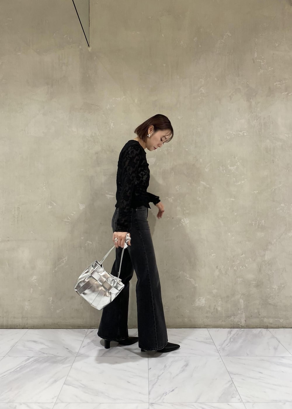 シルバー系のキャミソール、シルバー系のショルダーバッグ、ブラック系のデニムパンツを着用したレディースの秋コーディネートの3枚目の写真