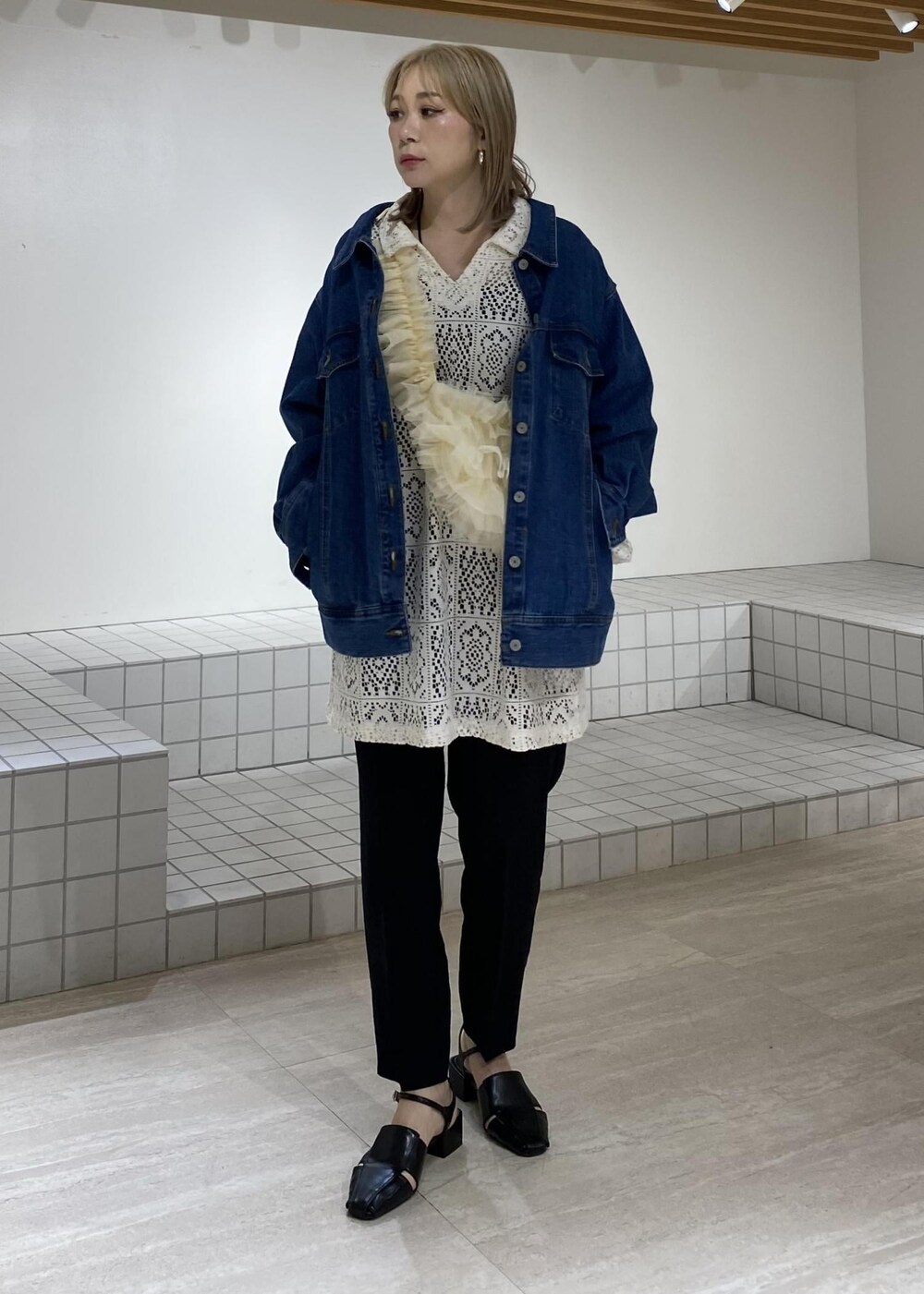 ブルー系のデニムジャケット、ブラック系のサンダル、ホワイト系のワンピースを着用したレディースの春コーディネートの3枚目の写真