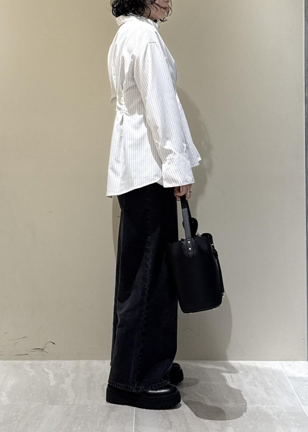 ブラック系のブーツ、ブラック系のショルダーバッグ、グレー系のデニムパンツを着用したレディースの秋コーディネートの3枚目の写真