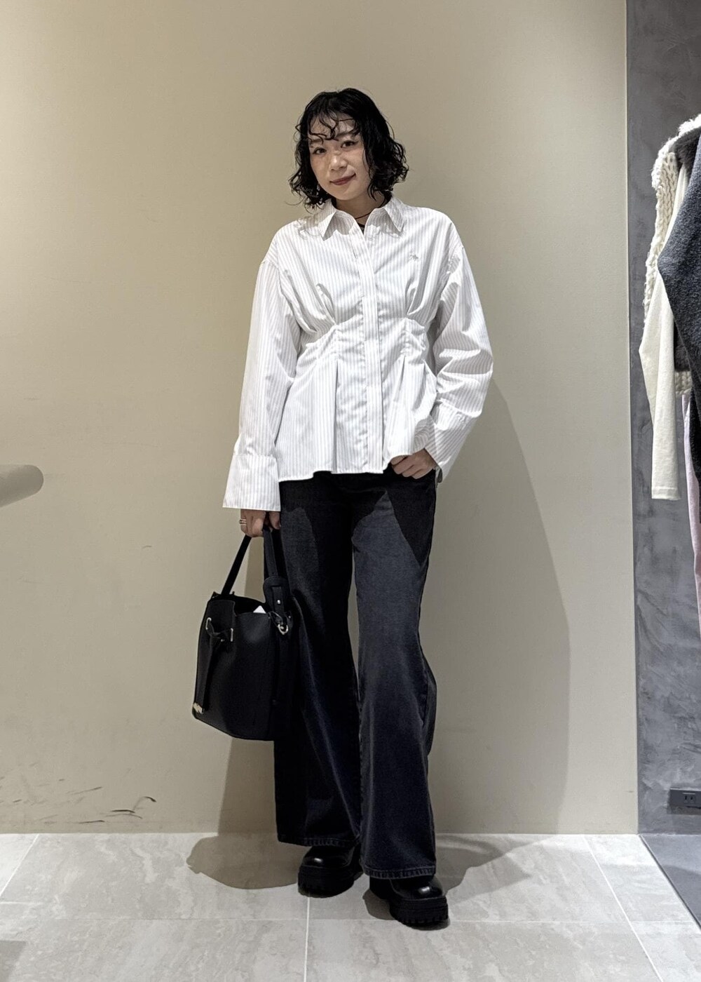 ブラック系のブーツ、ブラック系のショルダーバッグ、グレー系のデニムパンツを着用したレディースの秋コーディネートの6枚目の写真