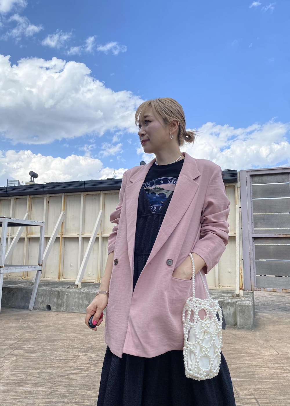 ベージュ系のサンダル、ブラック系のTシャツ/カットソー、ブラック系のジャンパースカートを着用したレディースの春コーディネートの2枚目の写真