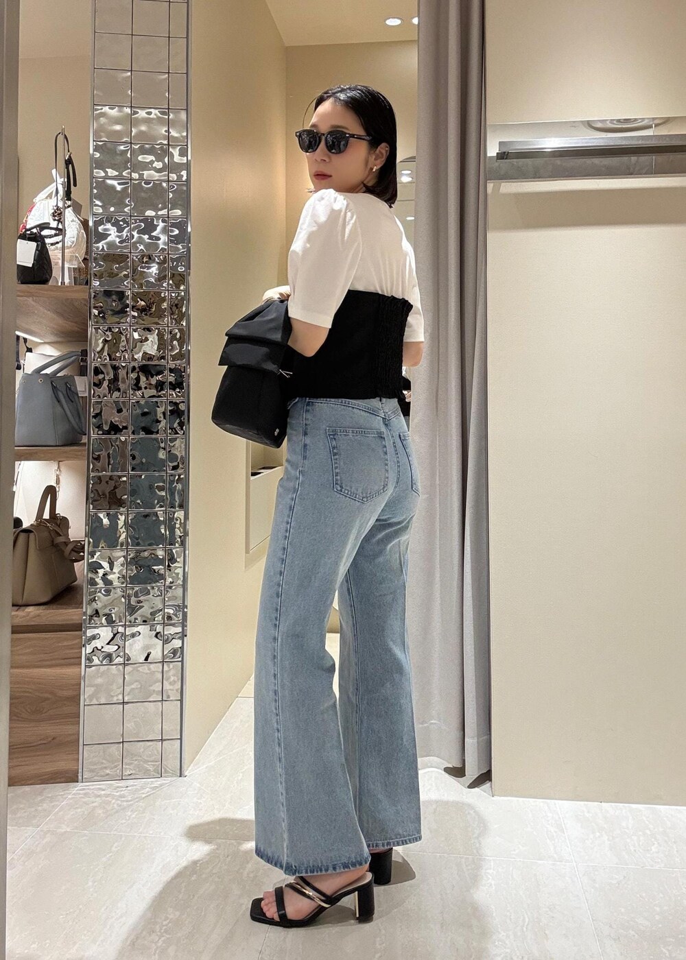 ブルー系のデニムパンツ、ブラック系のハンドバッグ、ブラック系のTシャツ/カットソーを着用したレディースの春コーディネートの4枚目の写真
