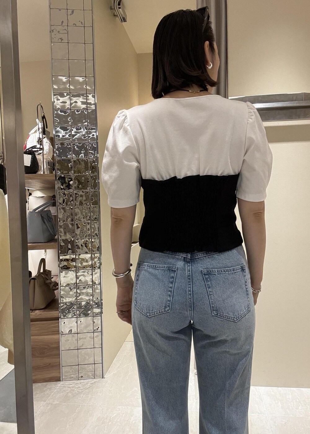 ブルー系のデニムパンツ、ブラック系のハンドバッグ、ブラック系のTシャツ/カットソーを着用したレディースの春コーディネートの6枚目の写真