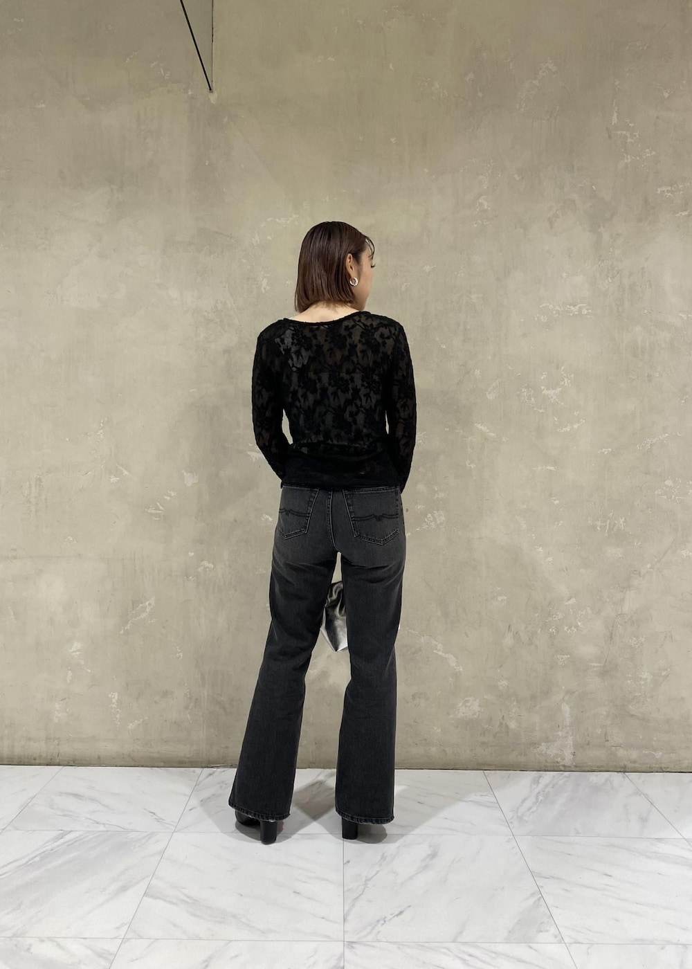 シルバー系のキャミソール、シルバー系のショルダーバッグ、ブラック系のデニムパンツを着用したレディースの秋コーディネートの2枚目の写真