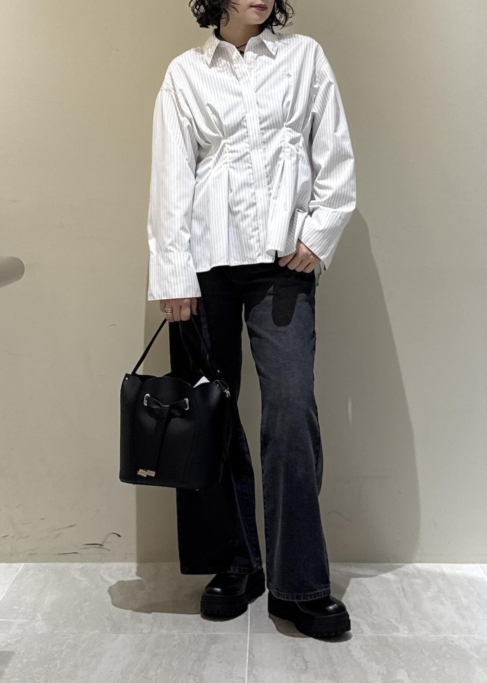 ブラック系のブーツ、ブラック系のショルダーバッグ、グレー系のデニムパンツを着用したレディースの秋コーディネートの2枚目の写真