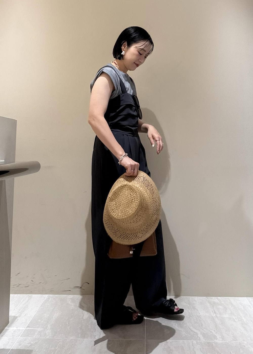 ブラウン系のショルダーバッグ、ブラック系のサンダル、グレー系のTシャツ/カットソーを着用したレディースの夏コーディネートの5枚目の写真