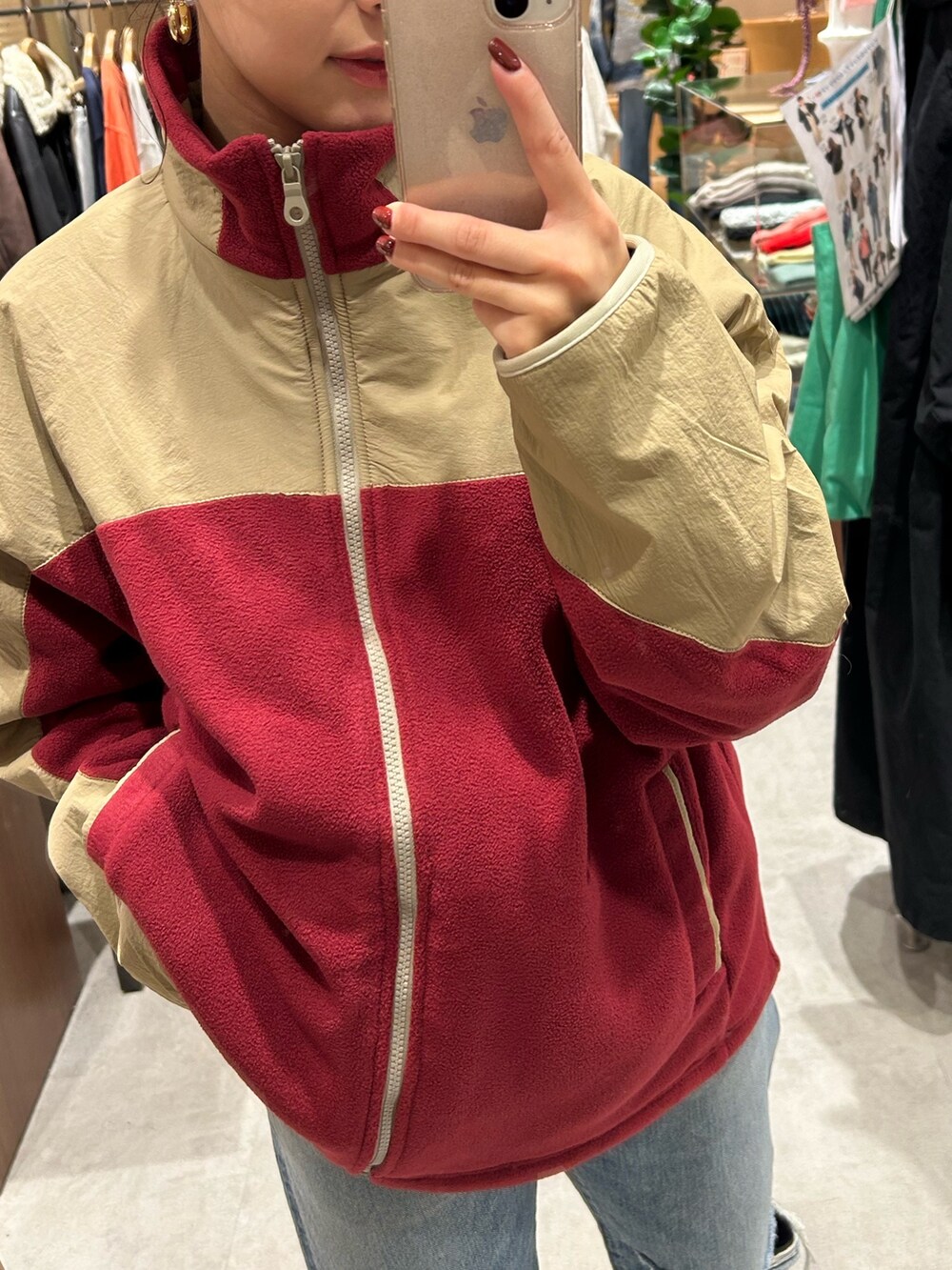 レッド系のブルゾン、ブルー系のデニムパンツを着用したレディースの秋コーディネートの2枚目の写真