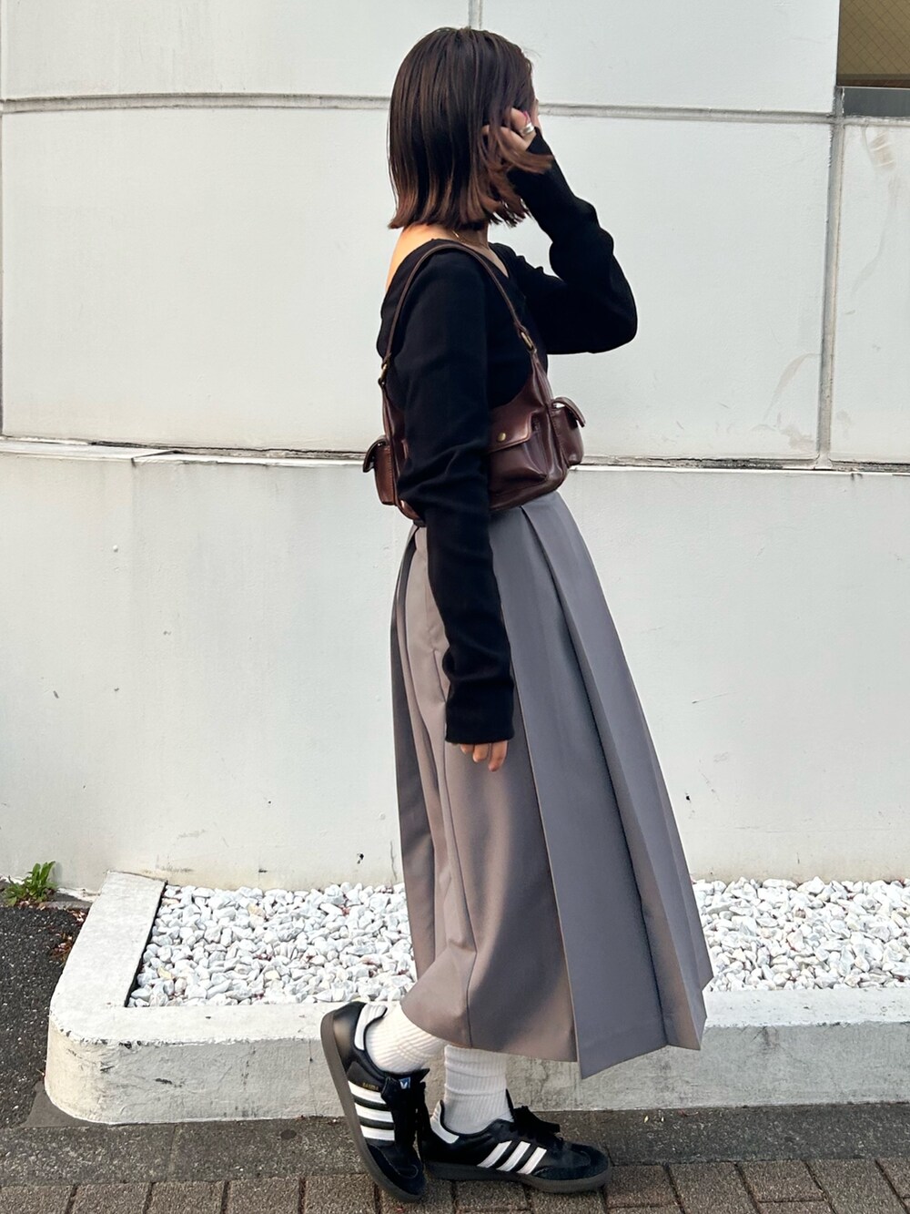 ブラック系のTシャツ/カットソー、グレー系のスカート、ブラウン系のハンドバッグを着用したレディースの秋コーディネートの2枚目の写真