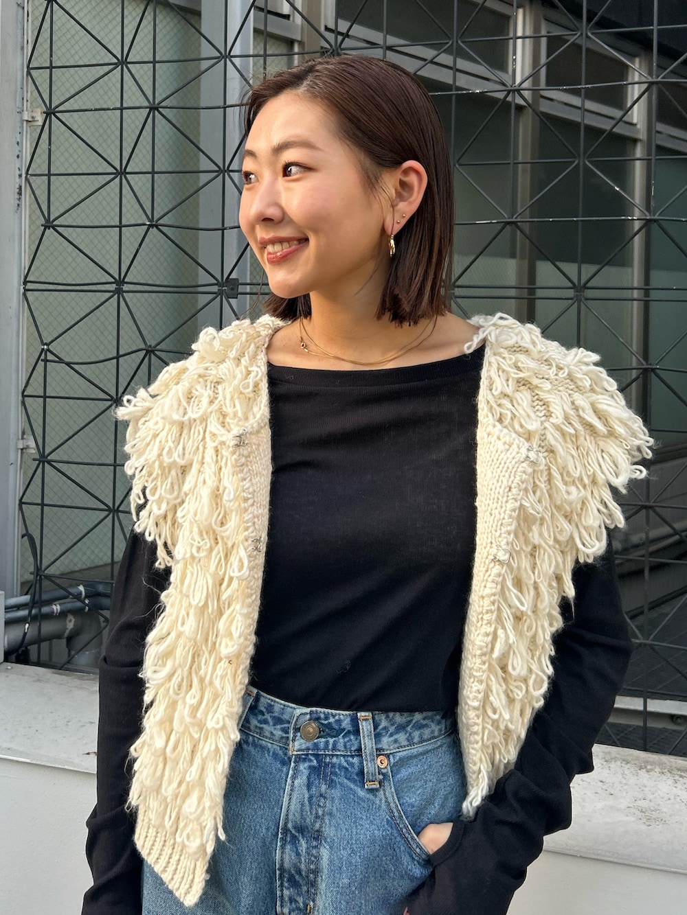 ホワイト系のベスト、ブラック系のTシャツ/カットソー、ブルー系のデニムパンツを着用したレディースの秋コーディネートの4枚目の写真