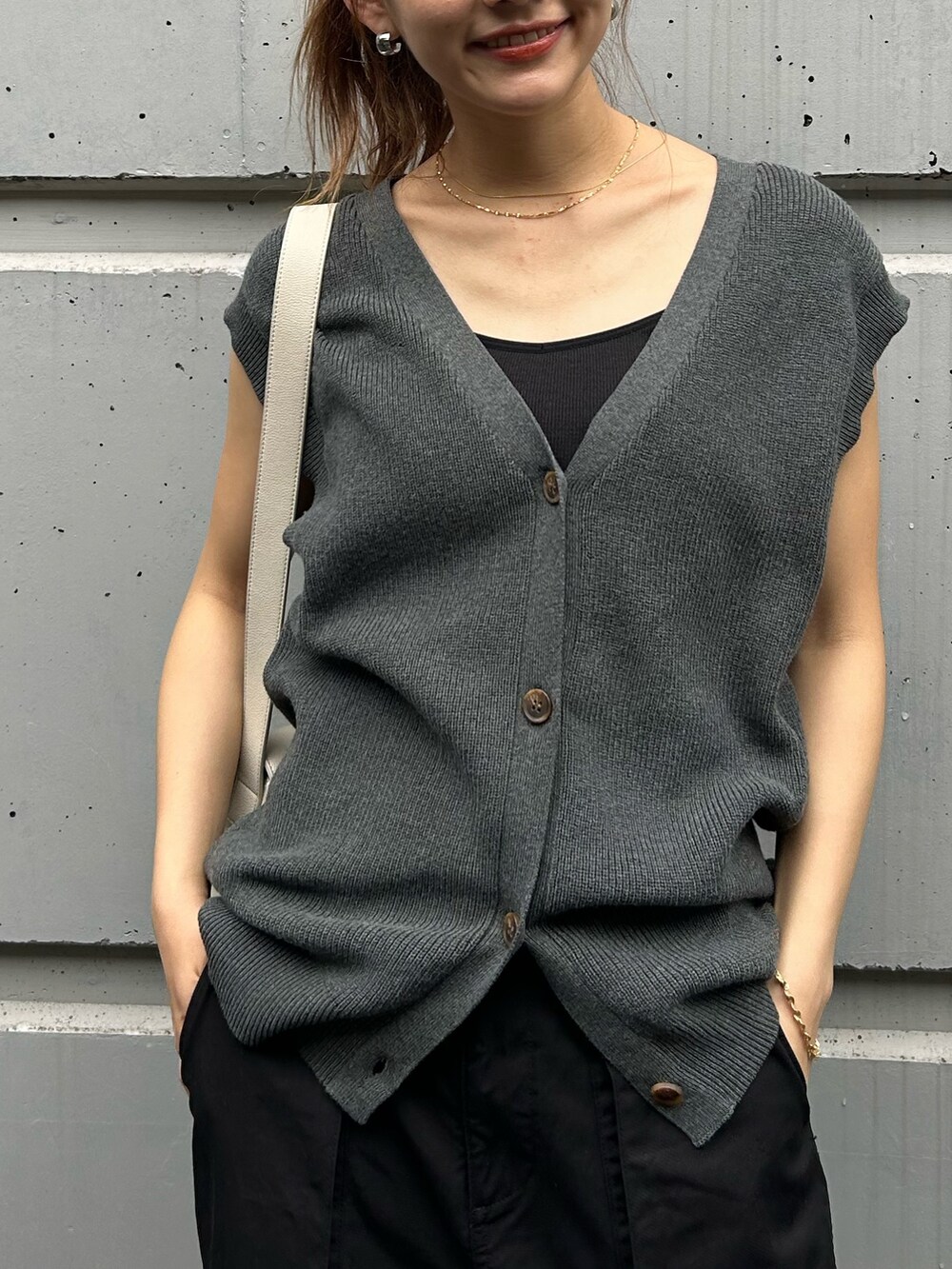 グレー系のベスト、ブラック系のカーゴパンツ、ホワイト系のショルダーバッグを着用したレディースの夏コーディネートの3枚目の写真