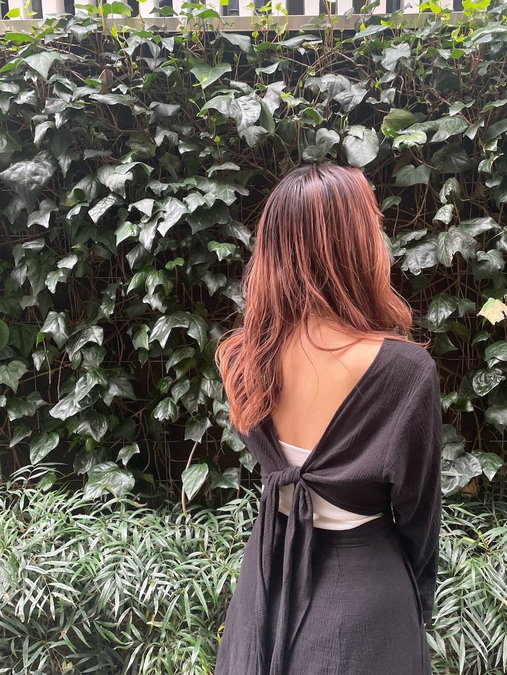 ホワイト系のハンドバッグ、ブラック系のワンピースを着用したレディースの春コーディネートの2枚目の写真