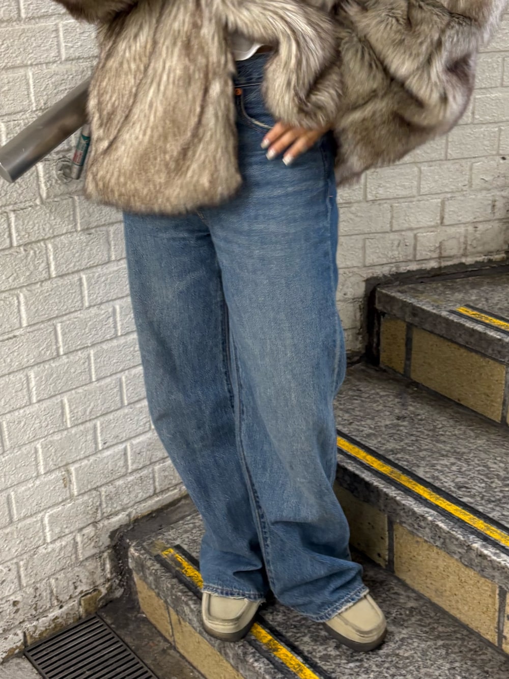 ベージュ系のダウンジャケット/コート、グリーン系のハンドバッグ、ブルー系のデニムパンツを着用したレディースの秋コーディネートの5枚目の写真