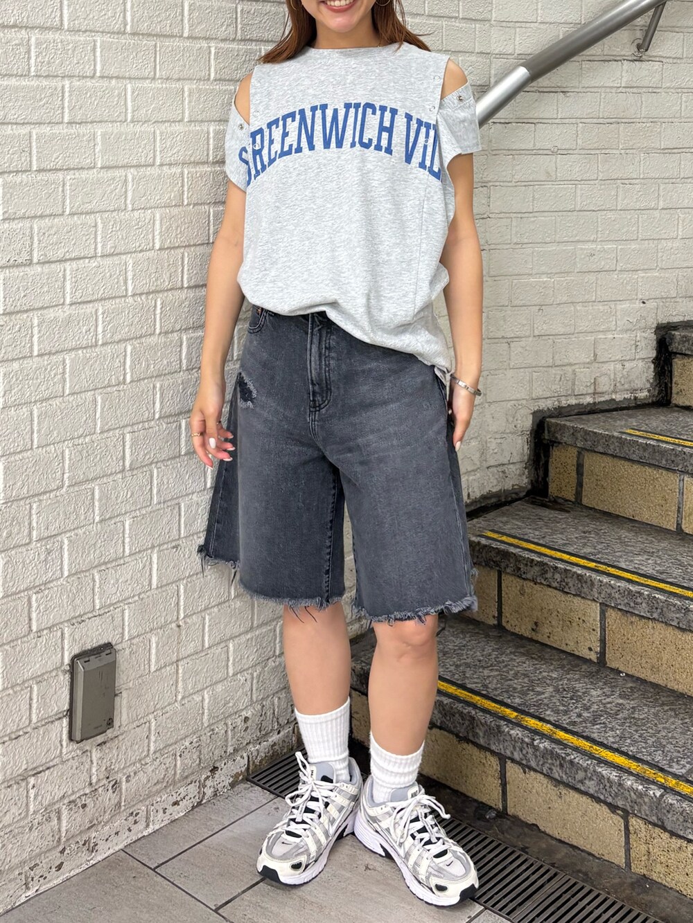 グレー系のタンクトップ、ブラック系のデニムパンツ、ホワイト系のキャップを着用したレディースの夏コーディネートの5枚目の写真