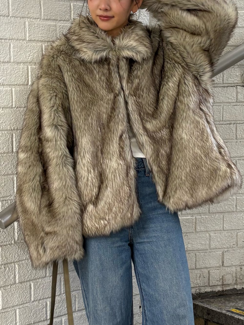 ベージュ系のダウンジャケット/コート、グリーン系のハンドバッグ、ブルー系のデニムパンツを着用したレディースの秋コーディネートの4枚目の写真