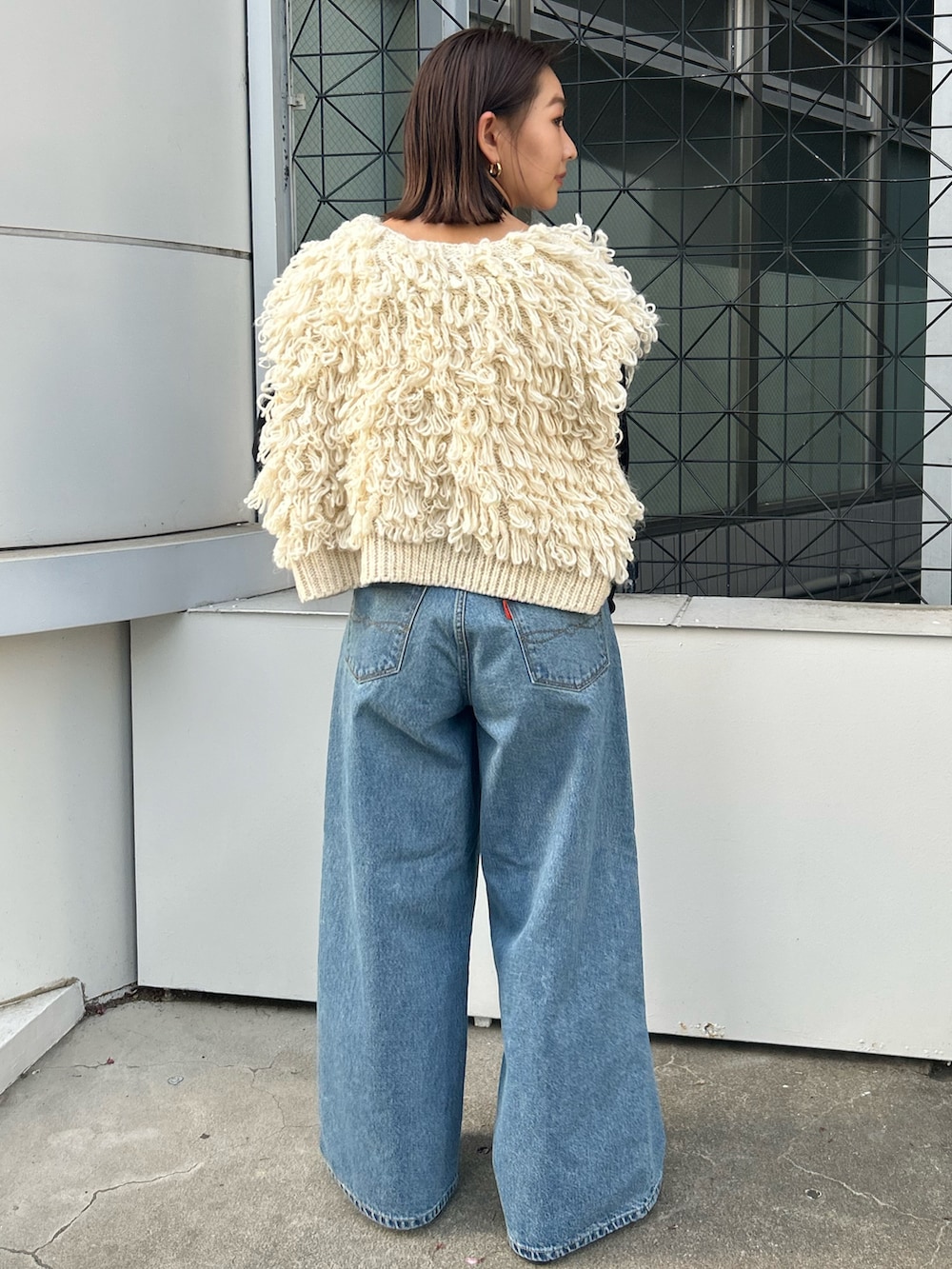 ホワイト系のベスト、ブラック系のTシャツ/カットソー、ブルー系のデニムパンツを着用したレディースの秋コーディネートの3枚目の写真