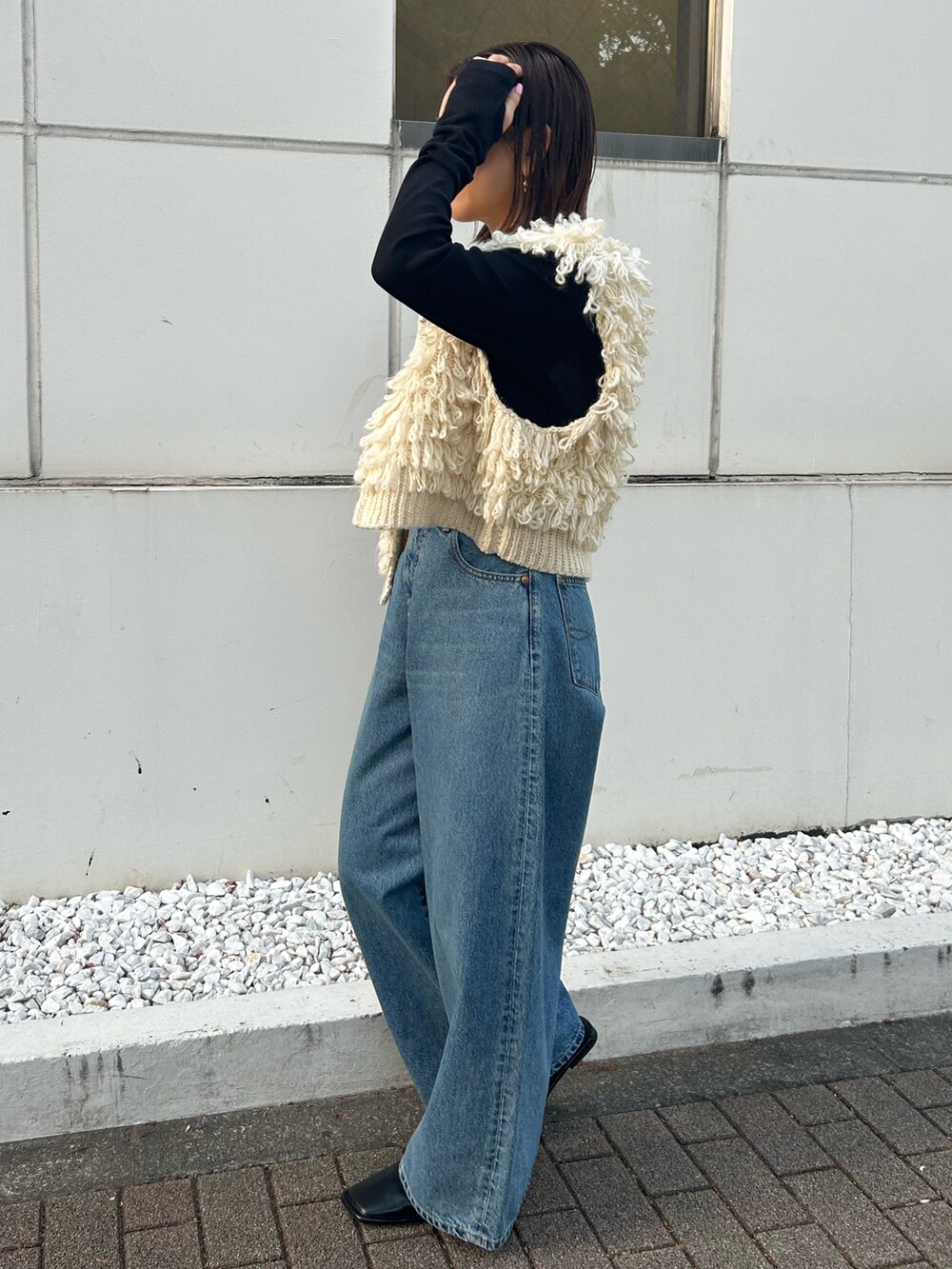 ホワイト系のベスト、ブラック系のTシャツ/カットソー、ブルー系のデニムパンツを着用したレディースの秋コーディネートの2枚目の写真