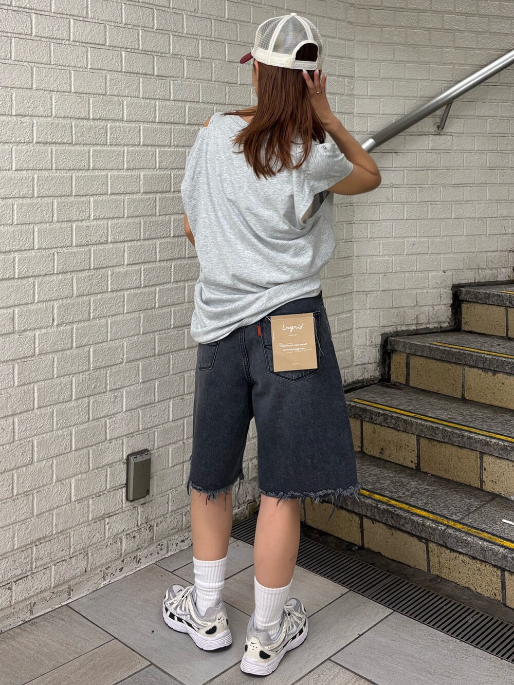 グレー系のタンクトップ、ブラック系のデニムパンツ、ホワイト系のキャップを着用したレディースの夏コーディネートの3枚目の写真