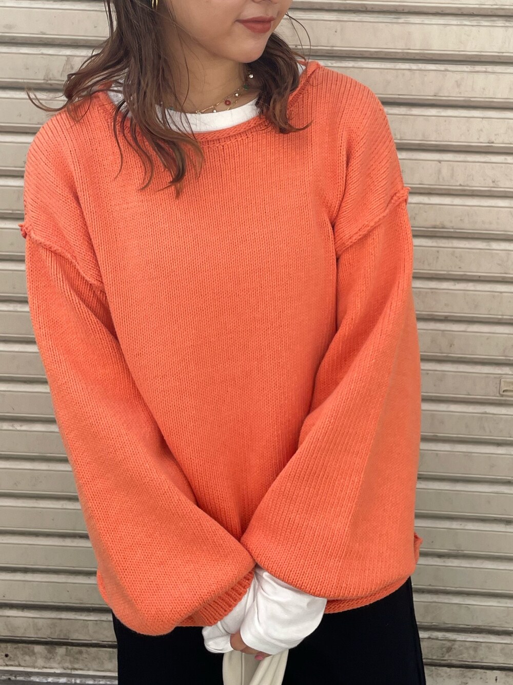 オレンジ系のニット/セーター、ホワイト系のTシャツ/カットソー、ホワイト系のハンドバッグを着用したレディースの秋コーディネートの2枚目の写真