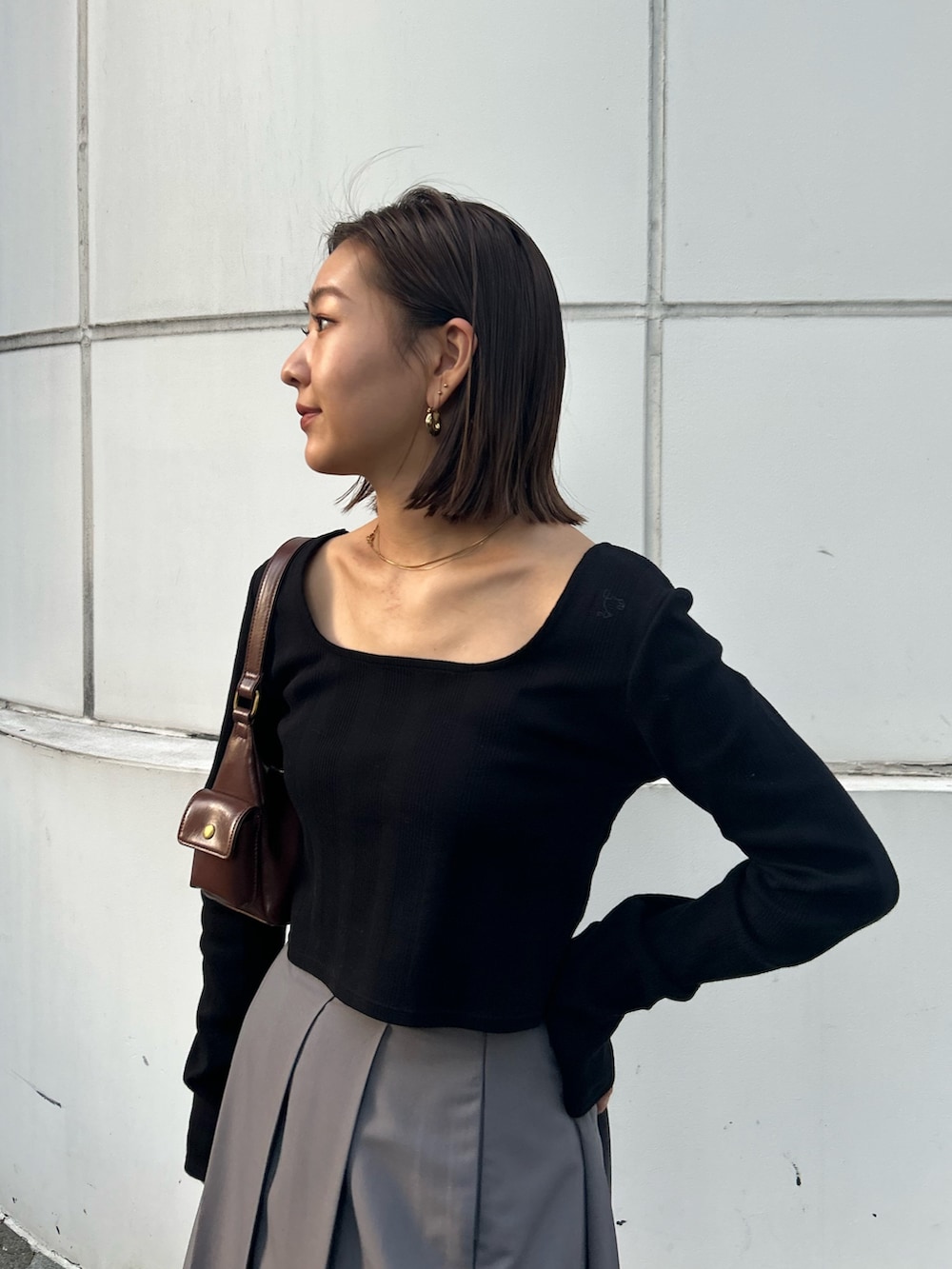 ブラック系のTシャツ/カットソー、グレー系のスカート、ブラウン系のハンドバッグを着用したレディースの秋コーディネートの4枚目の写真