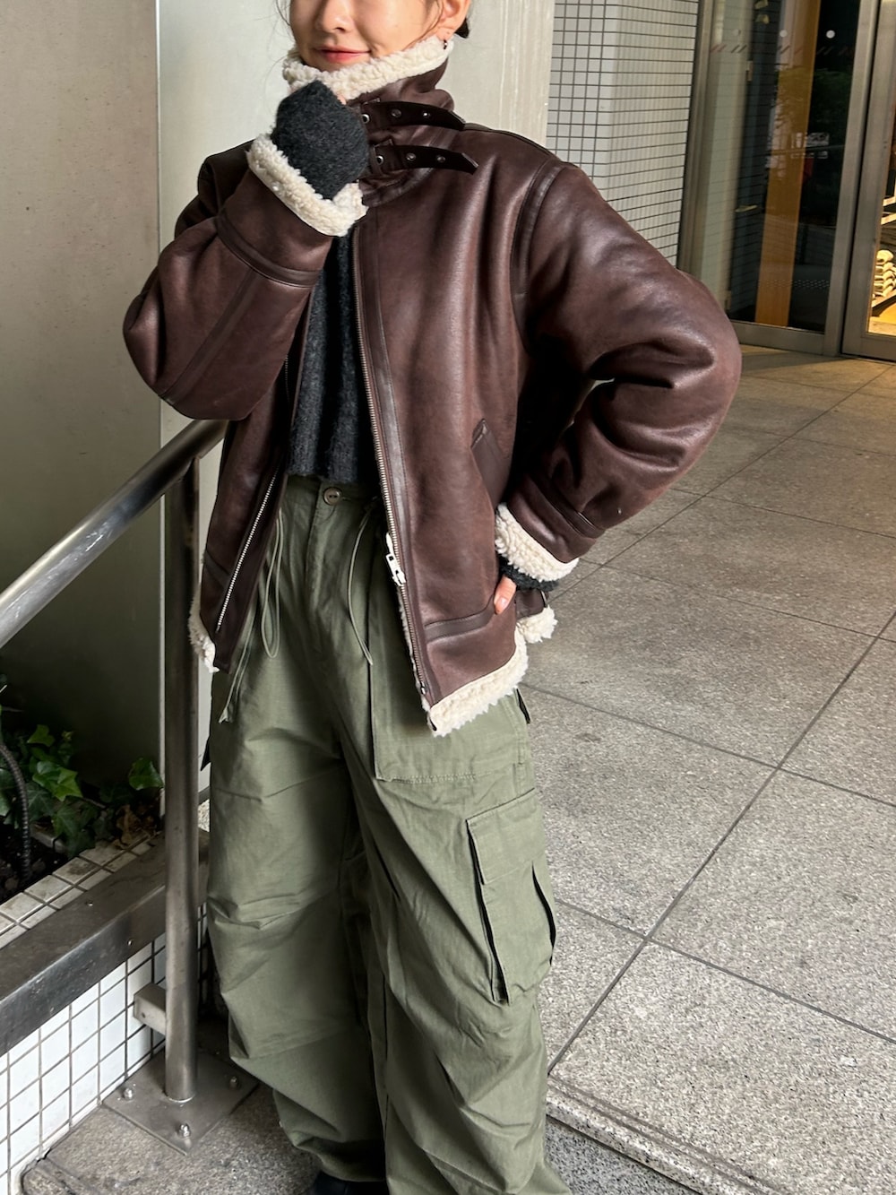 ブラウン系のムートンコート、グリーン系のカーゴパンツ、ブラック系のブーツを着用したレディースの冬コーディネートの2枚目の写真