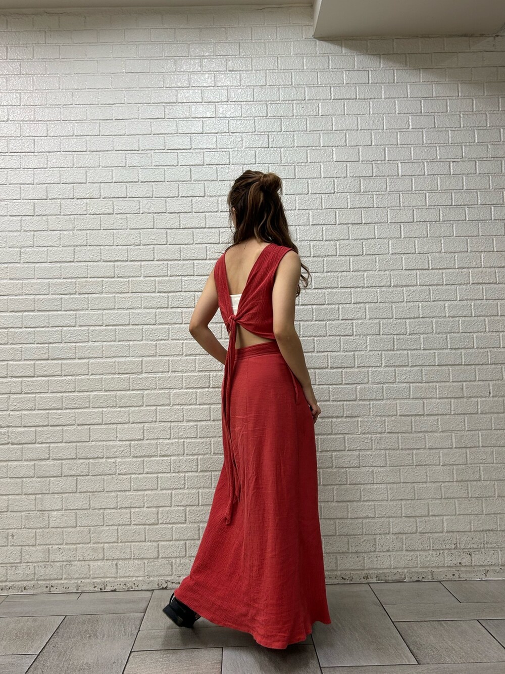 オレンジ系のワンピース、ホワイト系のキャミソールを着用したレディースの夏コーディネートの2枚目の写真