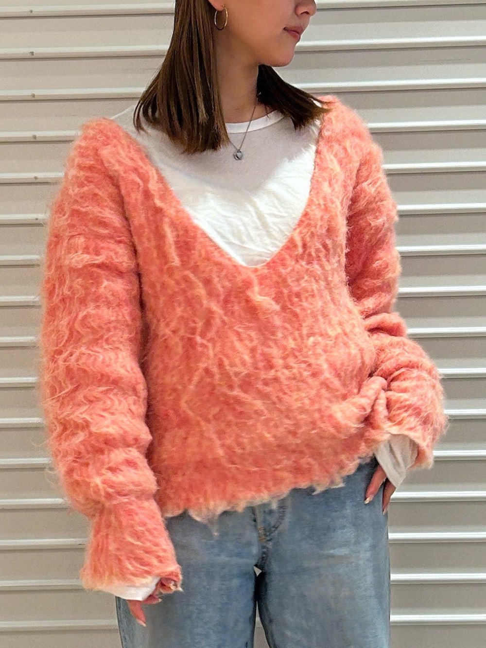 ピンク系のニット/セーター、ブルー系のデニムパンツを着用したレディースの冬コーディネートの4枚目の写真