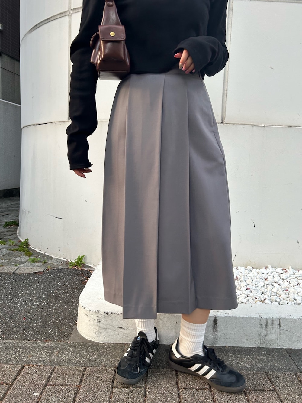 ブラック系のTシャツ/カットソー、グレー系のスカート、ブラウン系のハンドバッグを着用したレディースの秋コーディネートの5枚目の写真