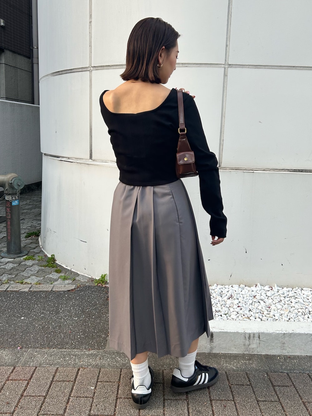 ブラック系のTシャツ/カットソー、グレー系のスカート、ブラウン系のハンドバッグを着用したレディースの秋コーディネートの3枚目の写真