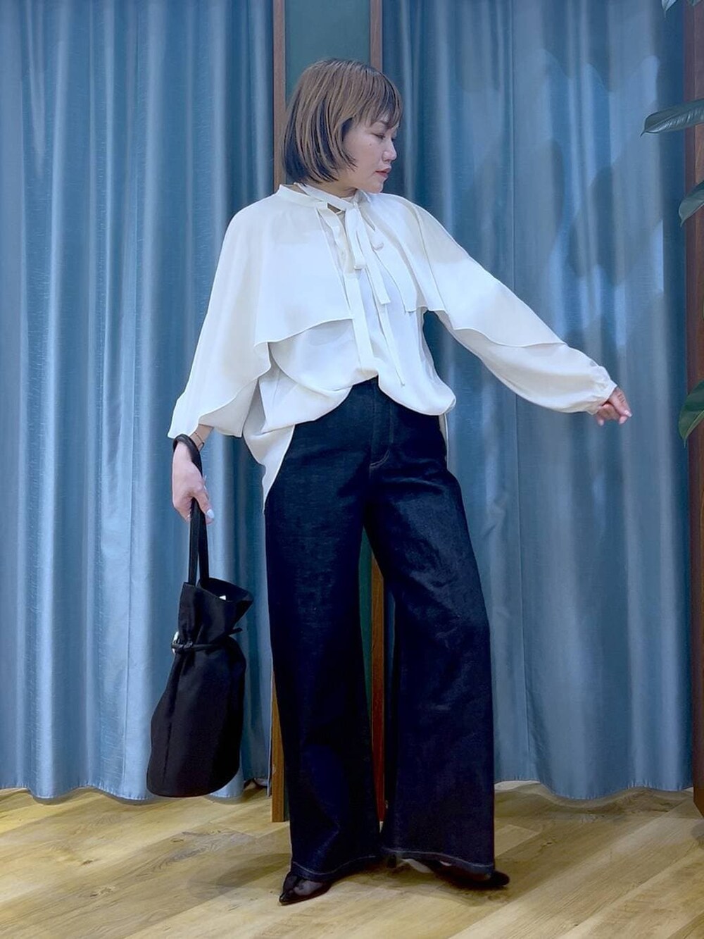 ブルー系のデニムパンツ、ホワイト系のシャツ/ブラウス、ブラック系のトートバッグを着用したレディースの冬コーディネートの3枚目の写真