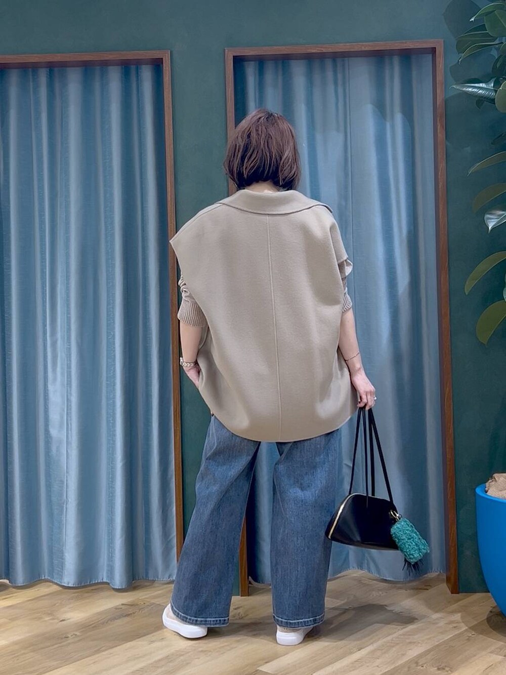 ブラック系のトートバッグ、ブルー系のデニムパンツ、ベージュ系のニット/セーターを着用したレディースの秋コーディネートの4枚目の写真