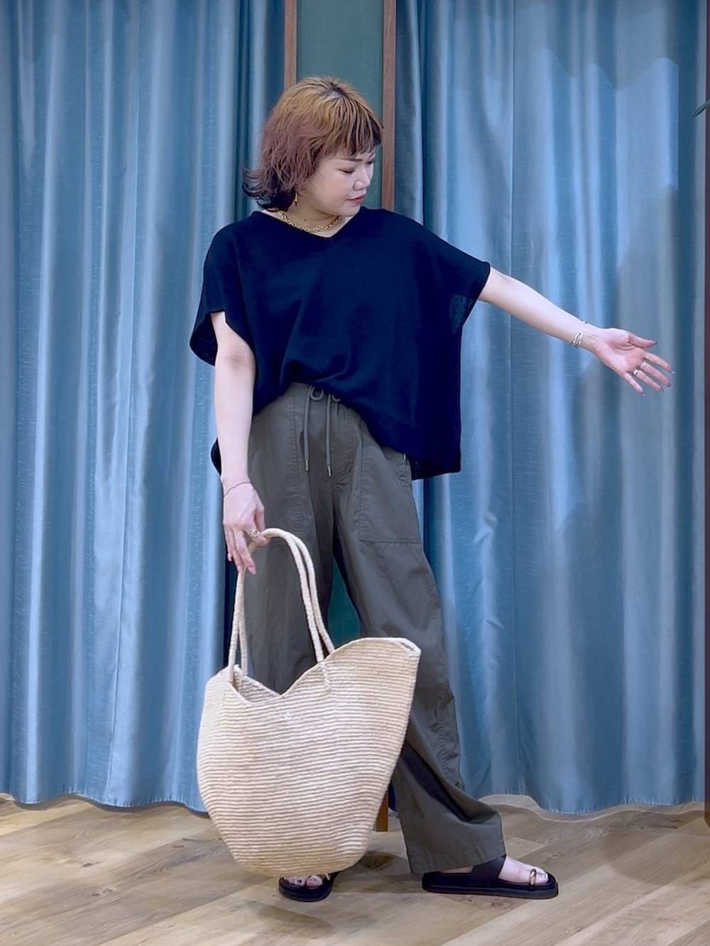 グリーン系のカーゴパンツ、ブラック系のサンダル、ベージュ系のかごバッグを着用したレディースの夏コーディネートの4枚目の写真